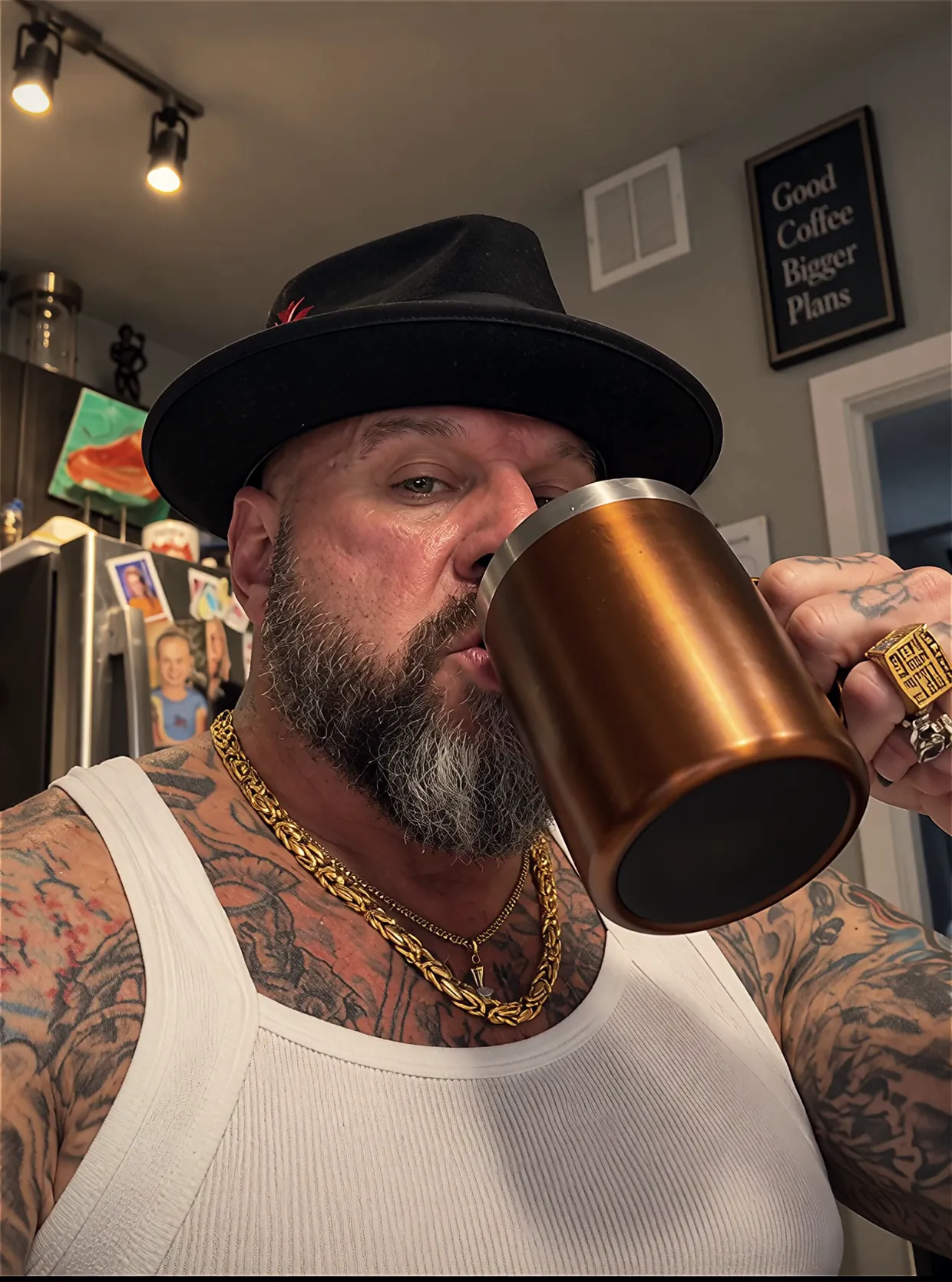 Face, in a black hat and gold chains, drinking from the copper mug in his kitchen.