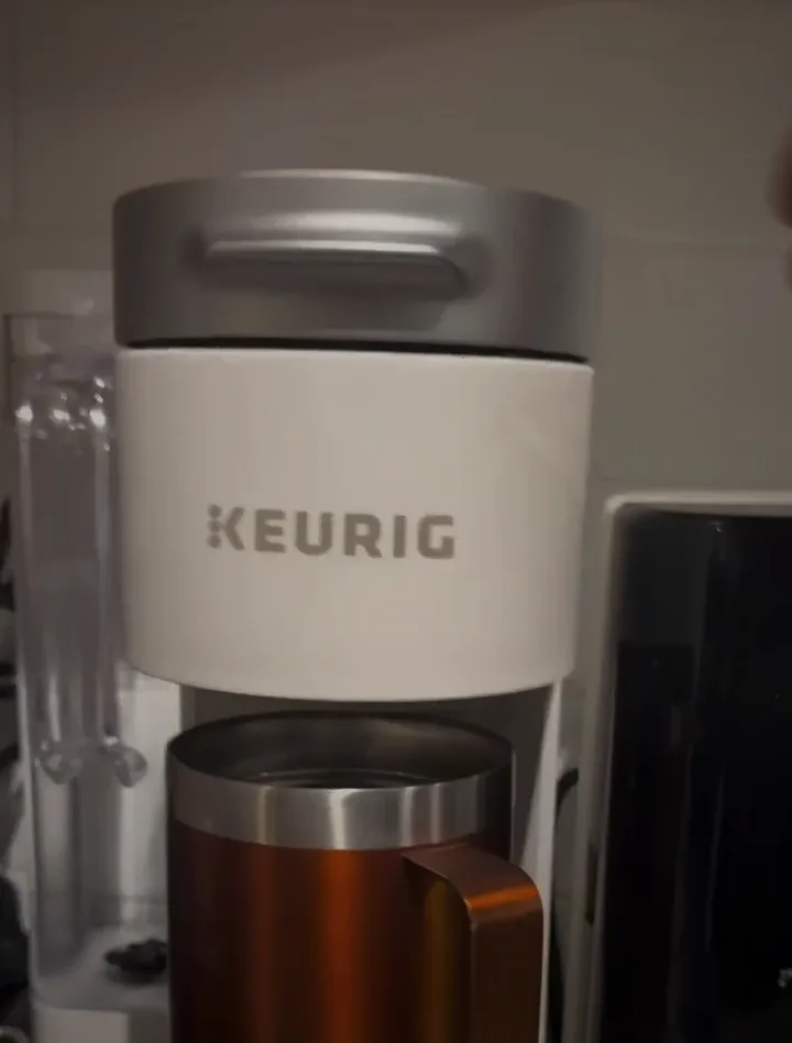 Face's hand closing the lid of his coffee maker, his copper mug underneath.